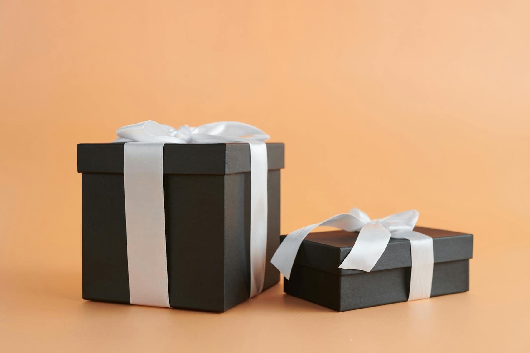Two elegant black gift boxes tied with white ribbon — a VIP loyalty reward