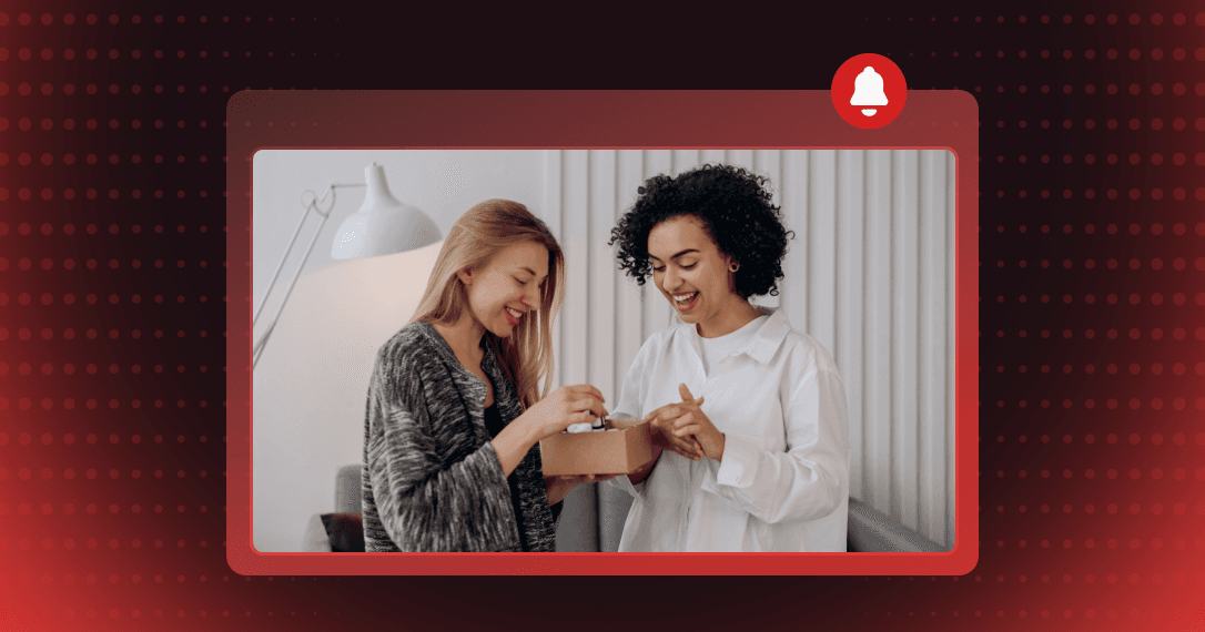 Two women laughing over a small gift box one hands to the other