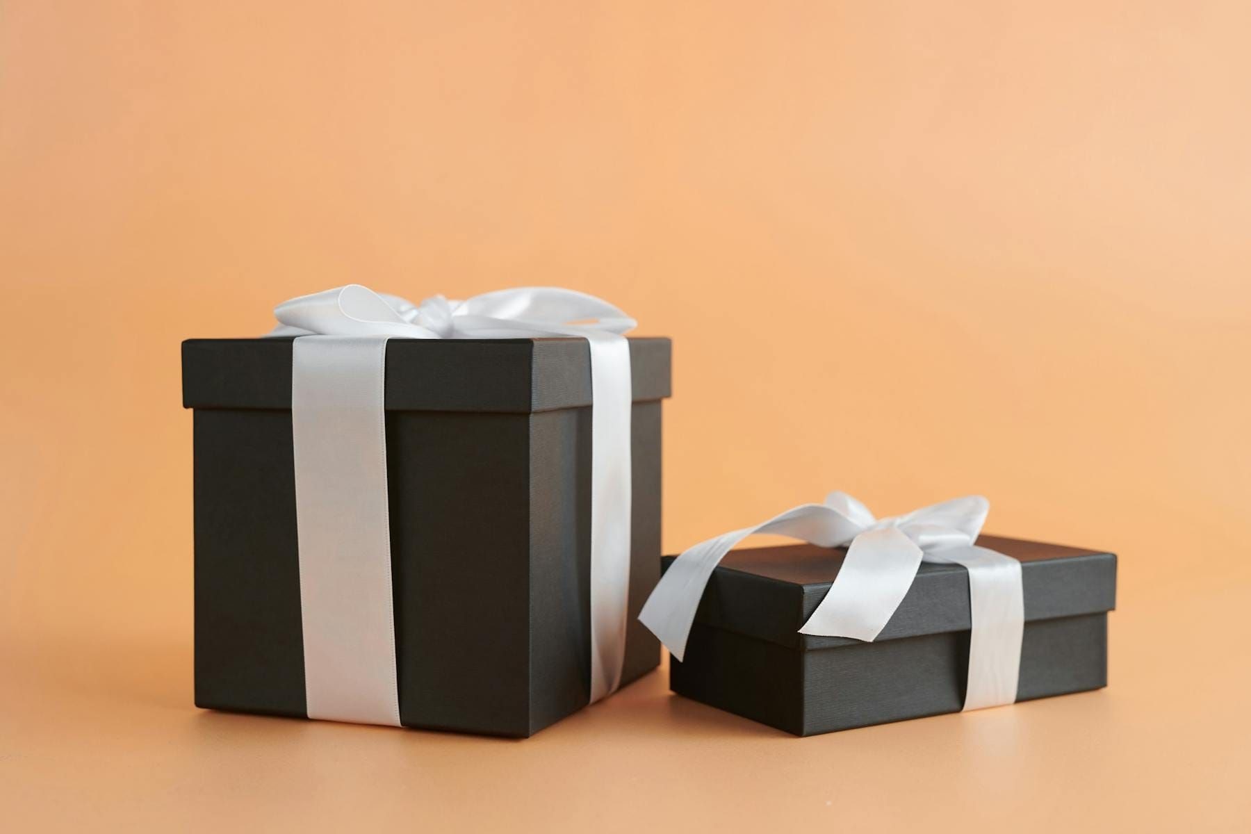 Two elegant black gift boxes tied with white ribbon — a VIP loyalty reward