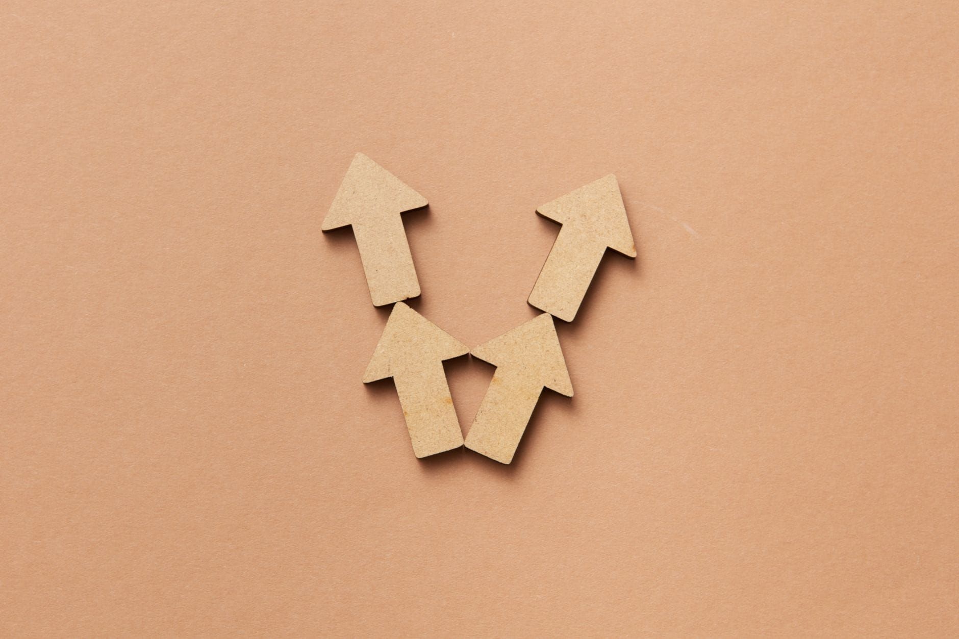 Cardboard arrows pointing upward on a brown surface