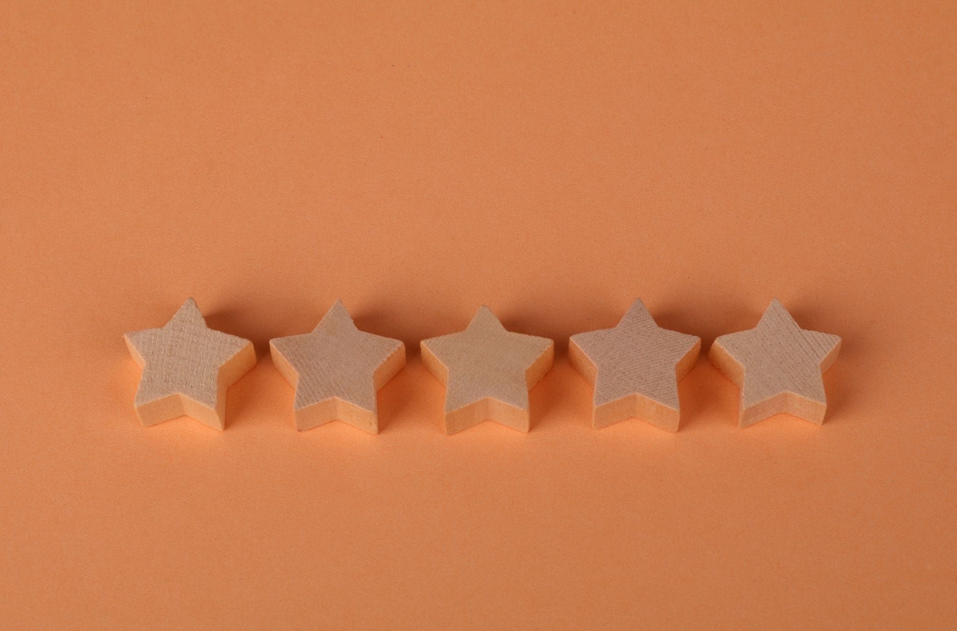 Five wooden stars arranged on a warm orange surface